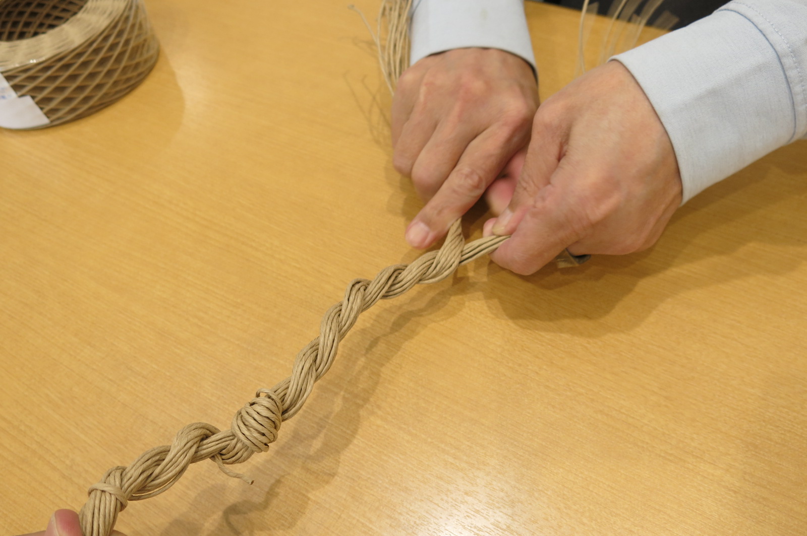 紙ひもをねじりながら結っている写真