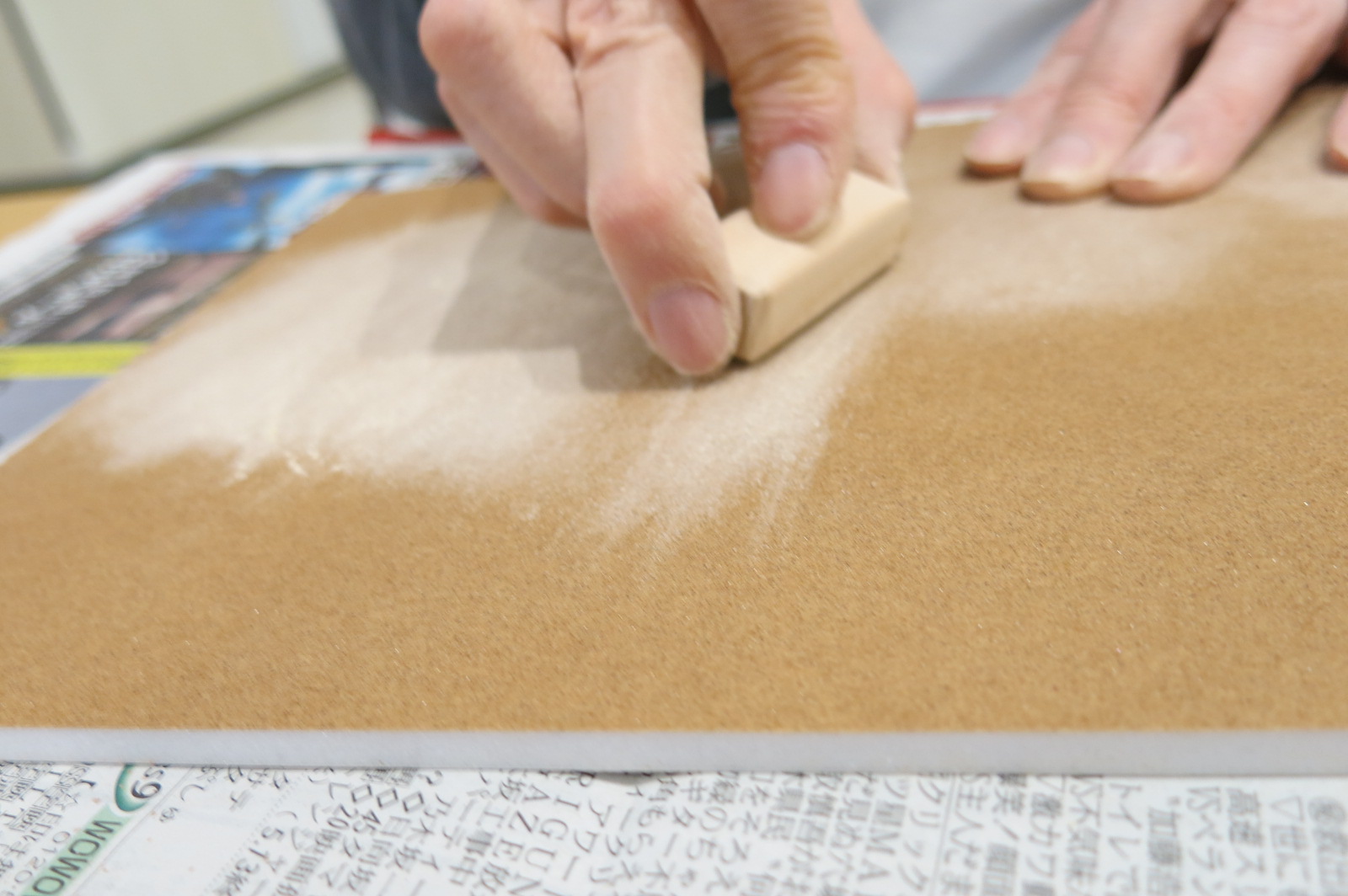 ヒノキの木材を板につけたやすりで磨いている様子