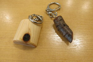 左に節目が見えるヒノキのキーホルダー、右に桜の枝のキーホルダー