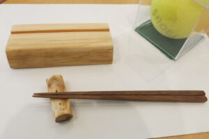 手前にボート型の箸置きと槐の箸。左奥に、色紙台。右奥には、色紙とセットで飾る、ブラインドテニスのボールが並んでいます。