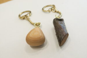 左にヒノキで作った雫型のキーホルダーと右に桜の枝のキーホルダーの写真