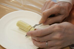 バナナをバターナイフで切っている写真