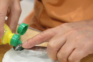 レモン汁を計量スプーンではかっている写真。スプーンの縁に指先を当てて、量を確認。