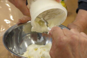 出来上がった生クリームをボウルにうつしている写真。ボウルの中に固まった生クリームが入っている。