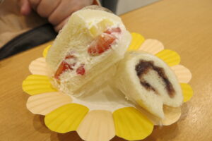 黄色の花びらのような縁の紙皿の上に、４分の１にカットされたフルーツサンドと餡バターをロールしたキャンディロールがのっている写真